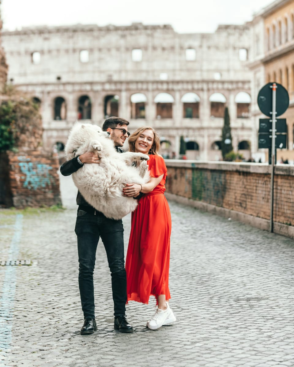 A couple laughing as he carries their fluffy Samoyed